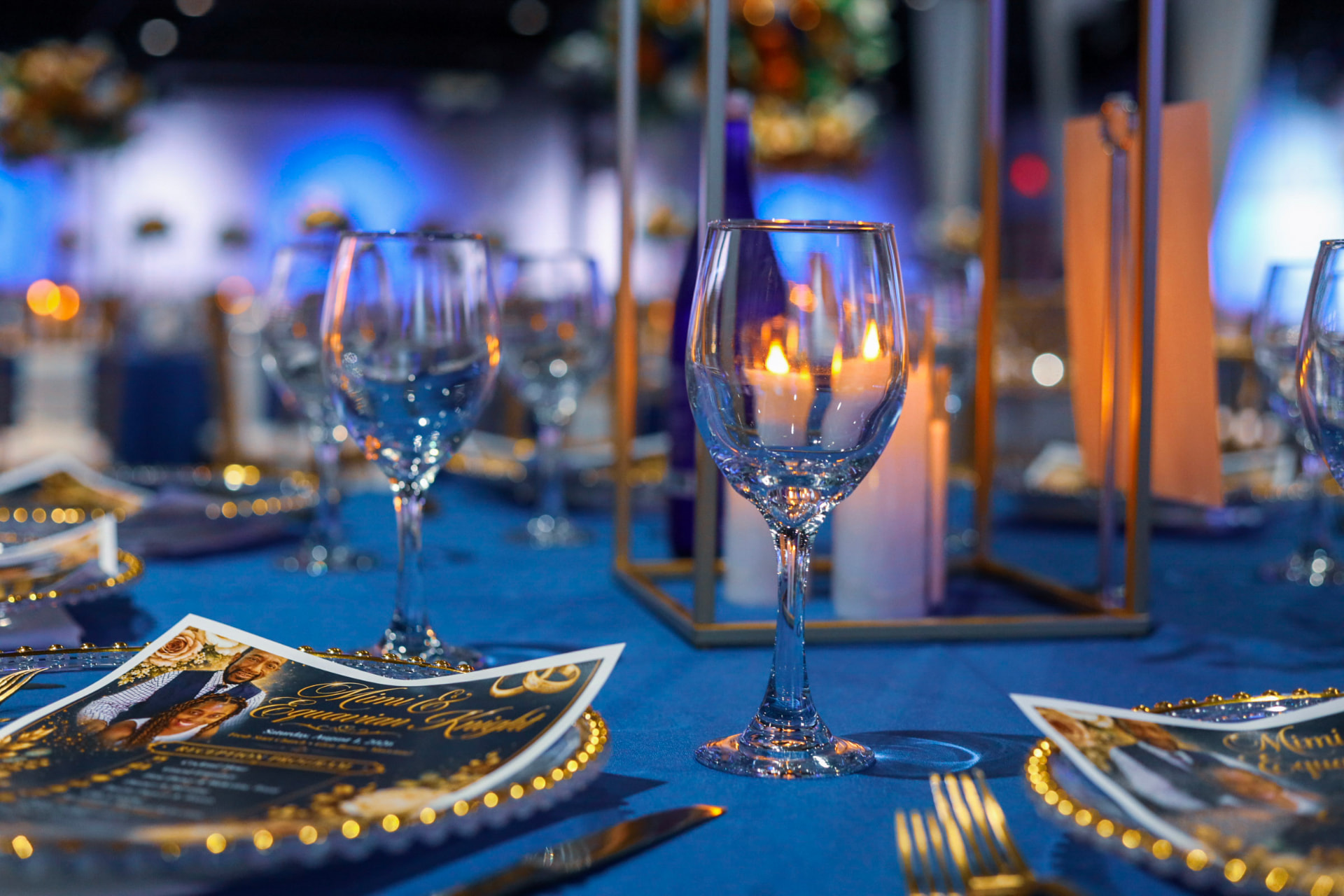 Candlelit reception table setting with blue linens and gold chargers