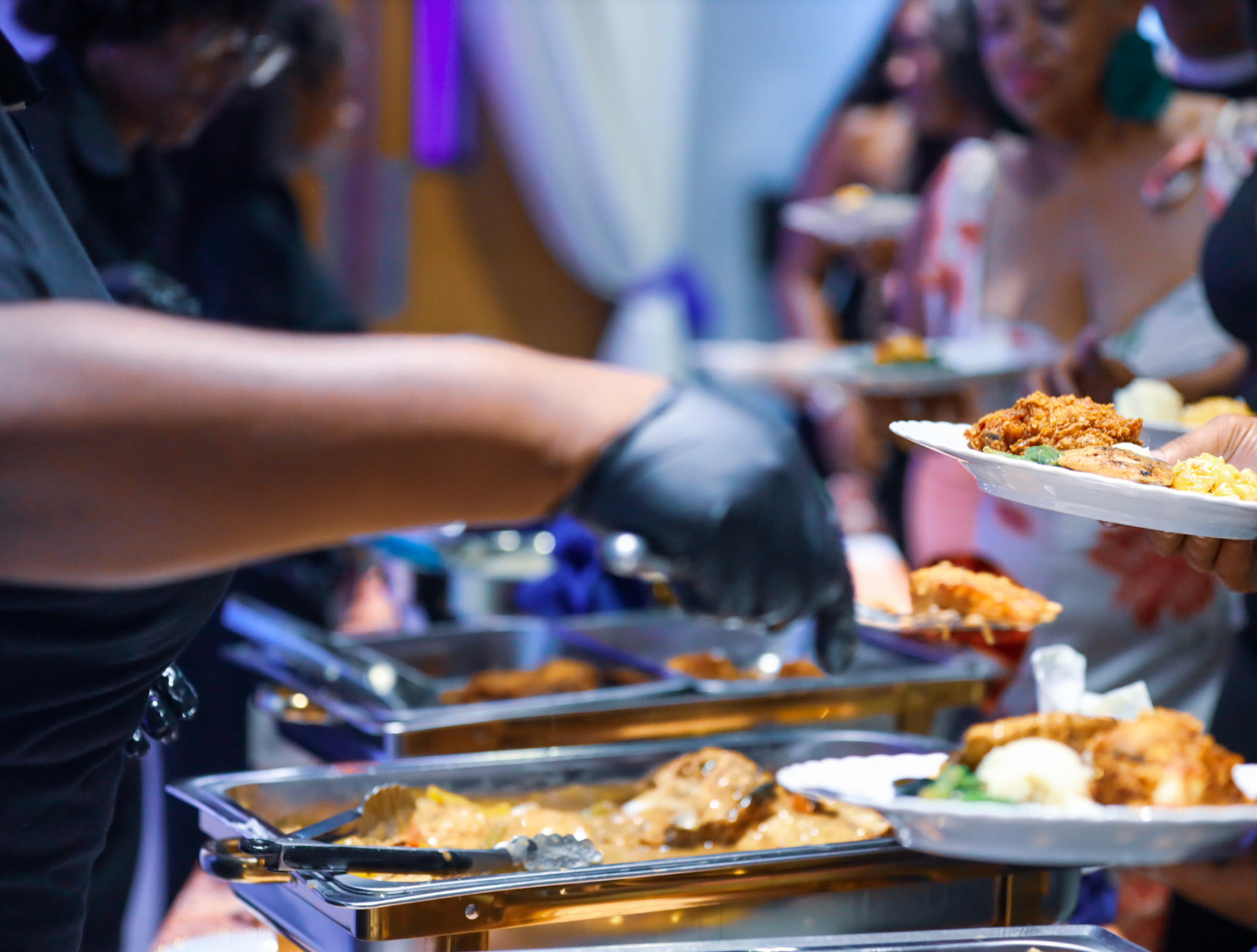 Catering staff serving plates at the buffet line